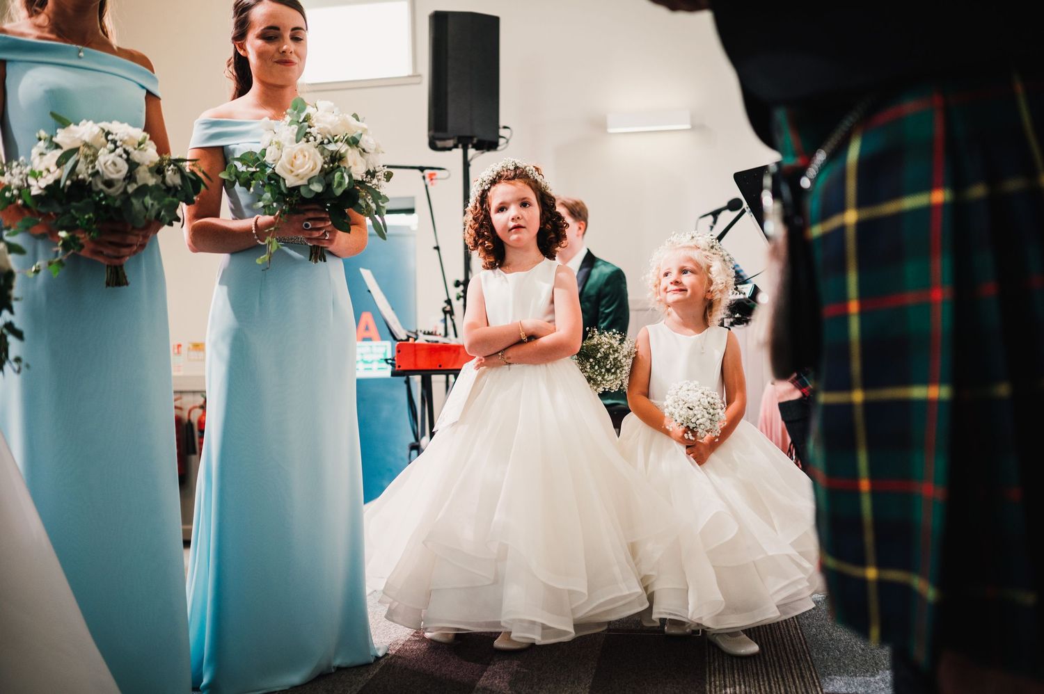 Wedding party members in light blue dresses and white gowns stand during church ceremony.