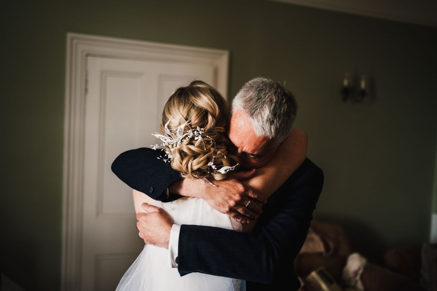 An intimate embrace captured from behind during wedding preparations.
