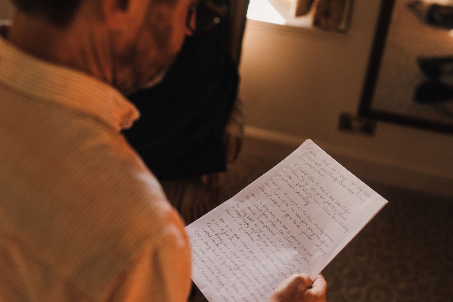 Someone reading from a handwritten note in dimly lit room.