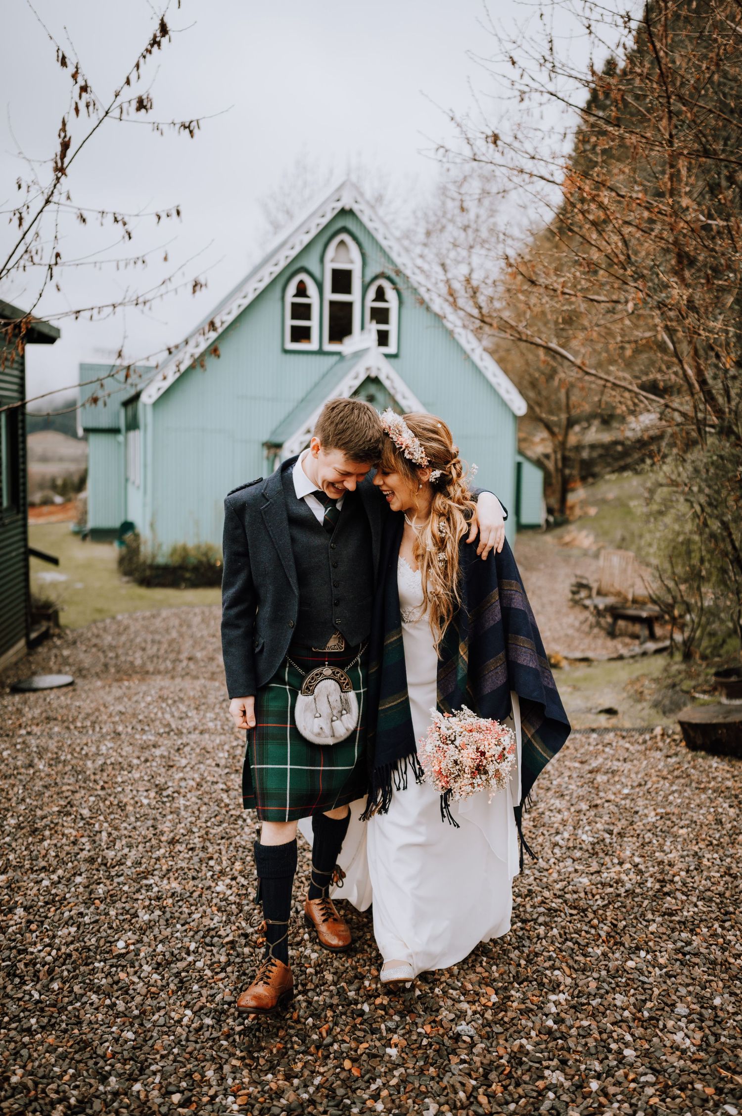 Intimate moment between newlyweds outside mint chapel with groom in traditional Scottish kilt.