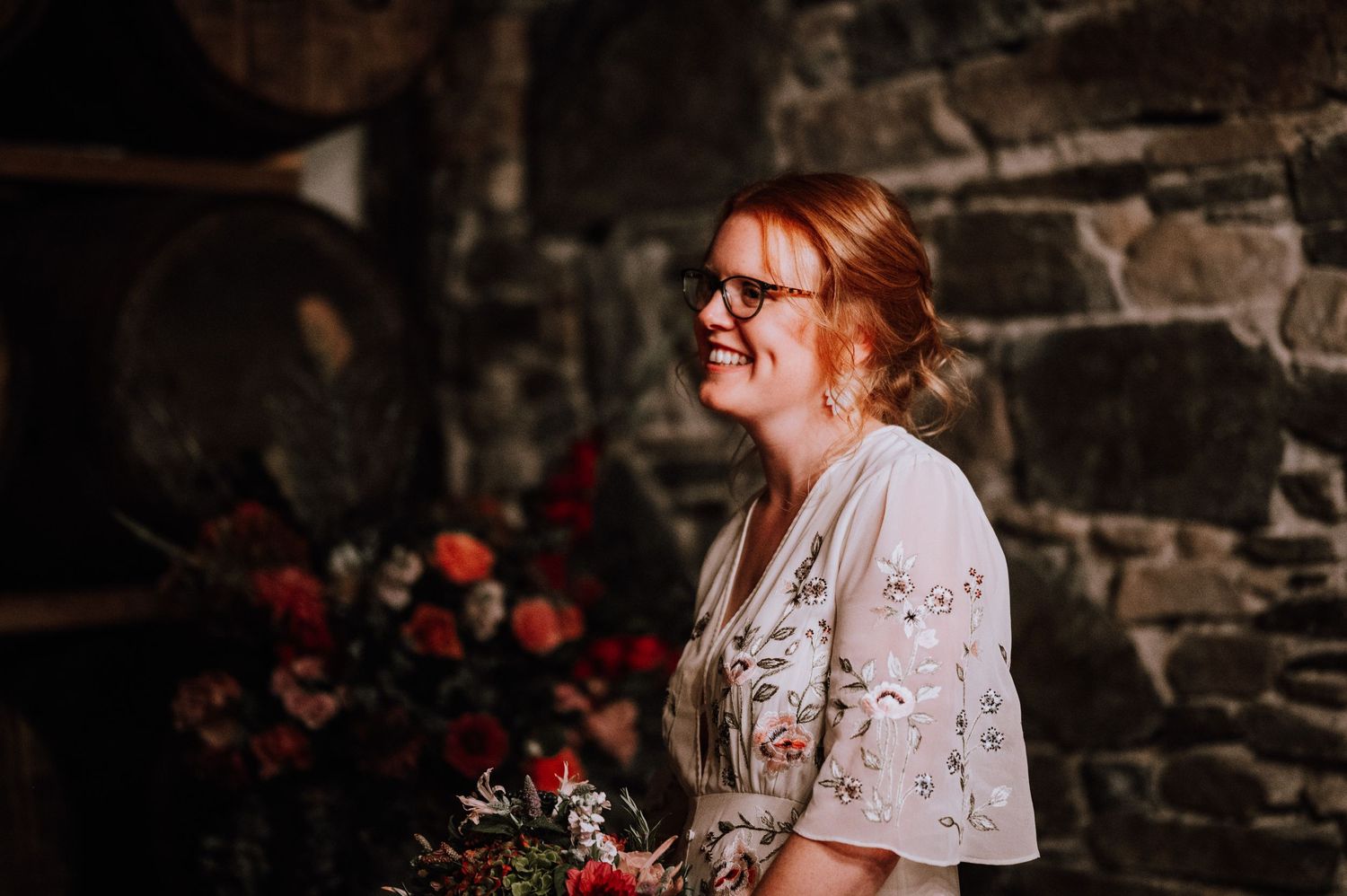 Joyful wedding moment captured in rustic wine cellar with romantic lighting.