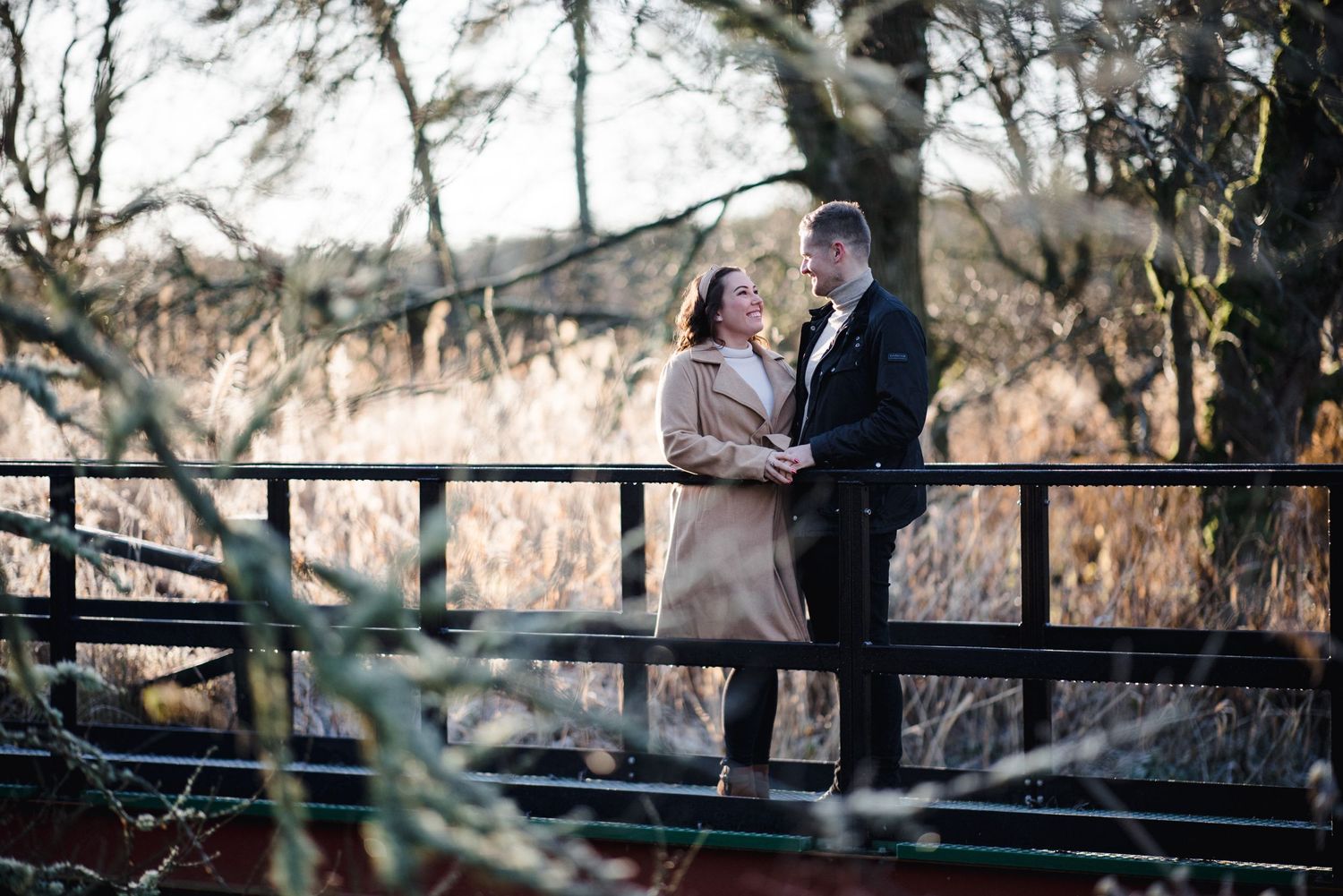 A couple shares a tender moment on a wooden bridge during their engagement session.