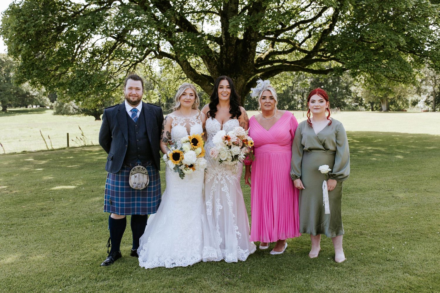 Fasque Castle Wedding Photography. Wedding party poses for group photos under large tree in outdoor garden setting.