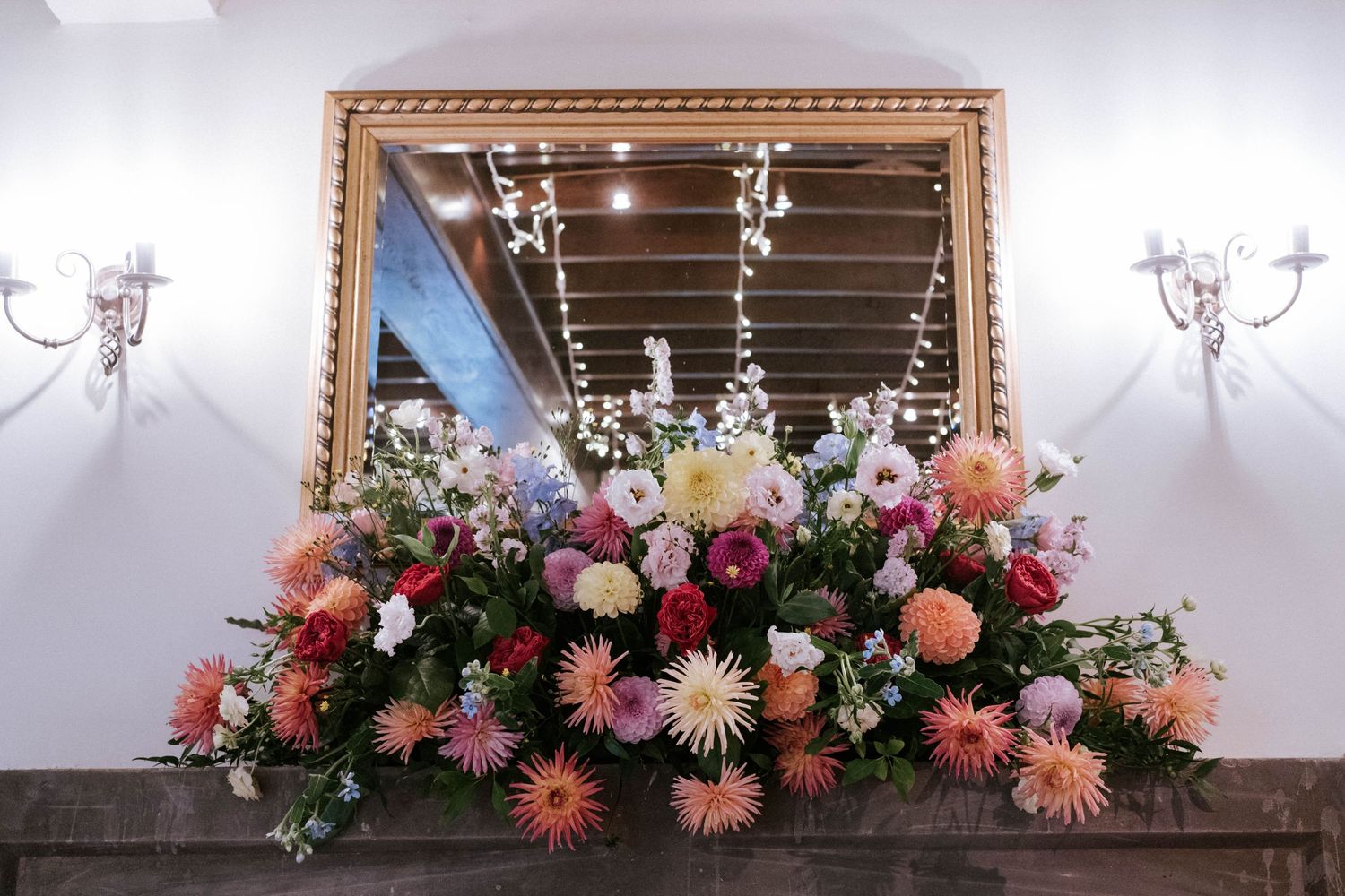 Luxurious floral arrangement with pink and coral blooms adorning a gilded mirror.