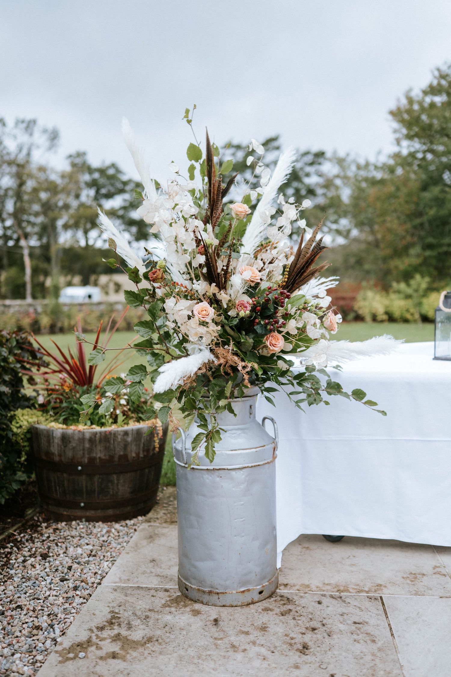 Rustic floral arrangements in galvanized metal containers displayed on a gravel surface.