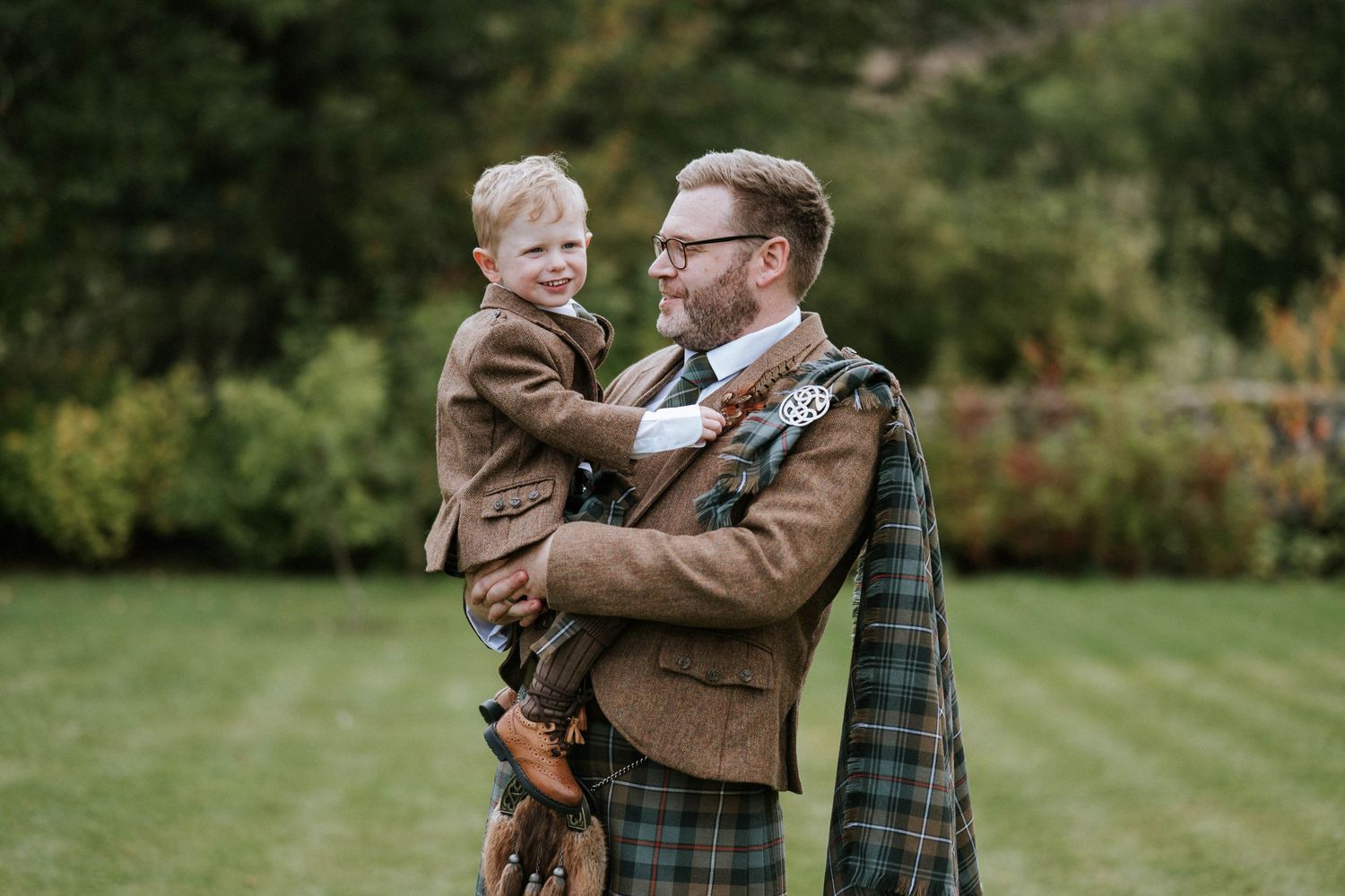 Family embracing outdoors in autumn with brown and plaid clothing.