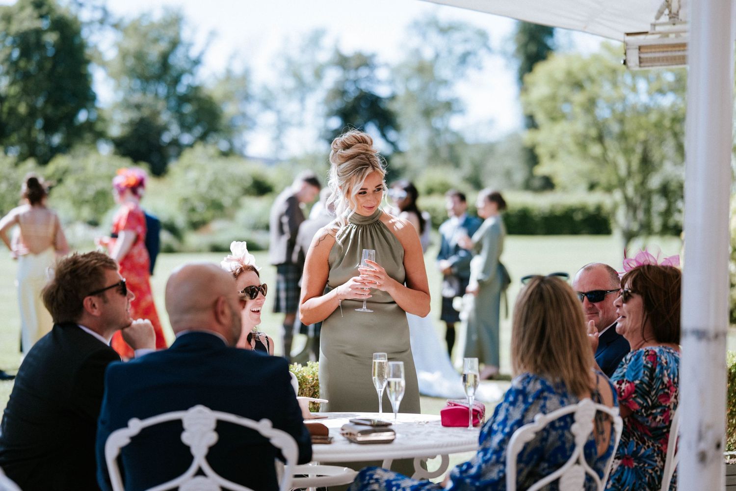Wedding guests enjoying drinks and conversation at an outdoor reception table.