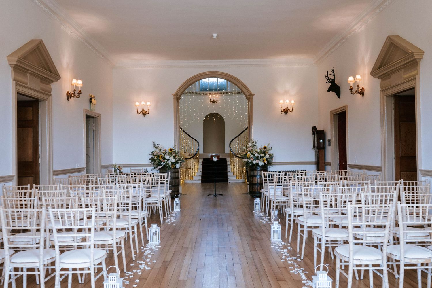 Wide-angle view of a pristine white wedding venue with symmetrical chair arrangements.