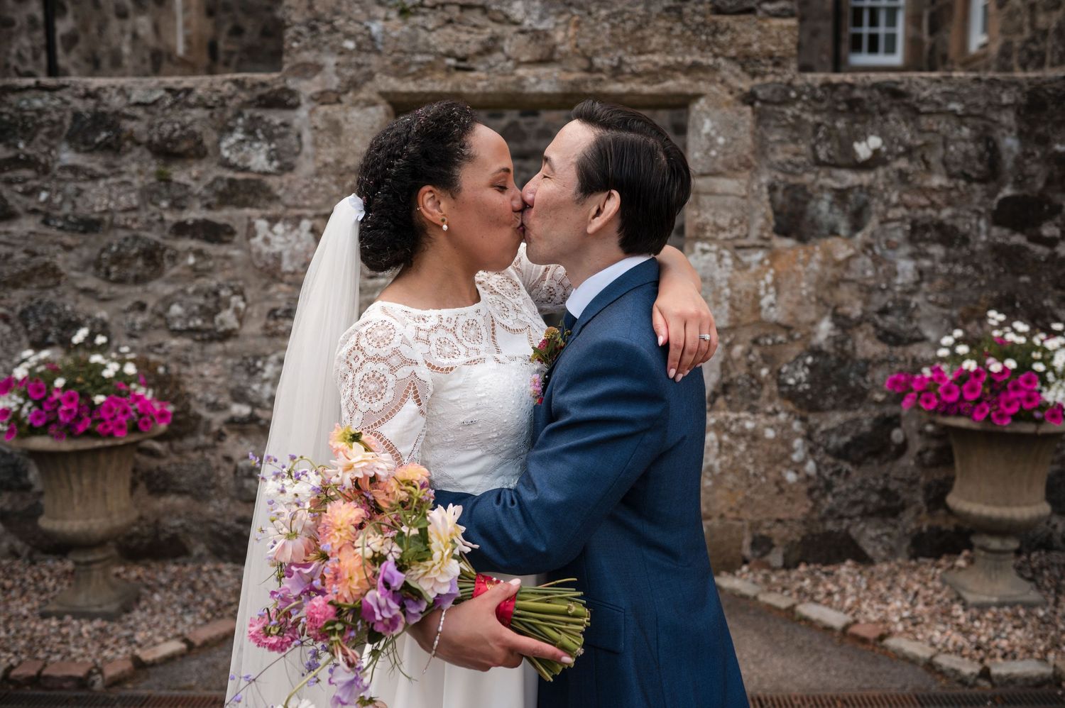 Stone wall backdrop with flowering plants creating a romantic wedding venue setting.