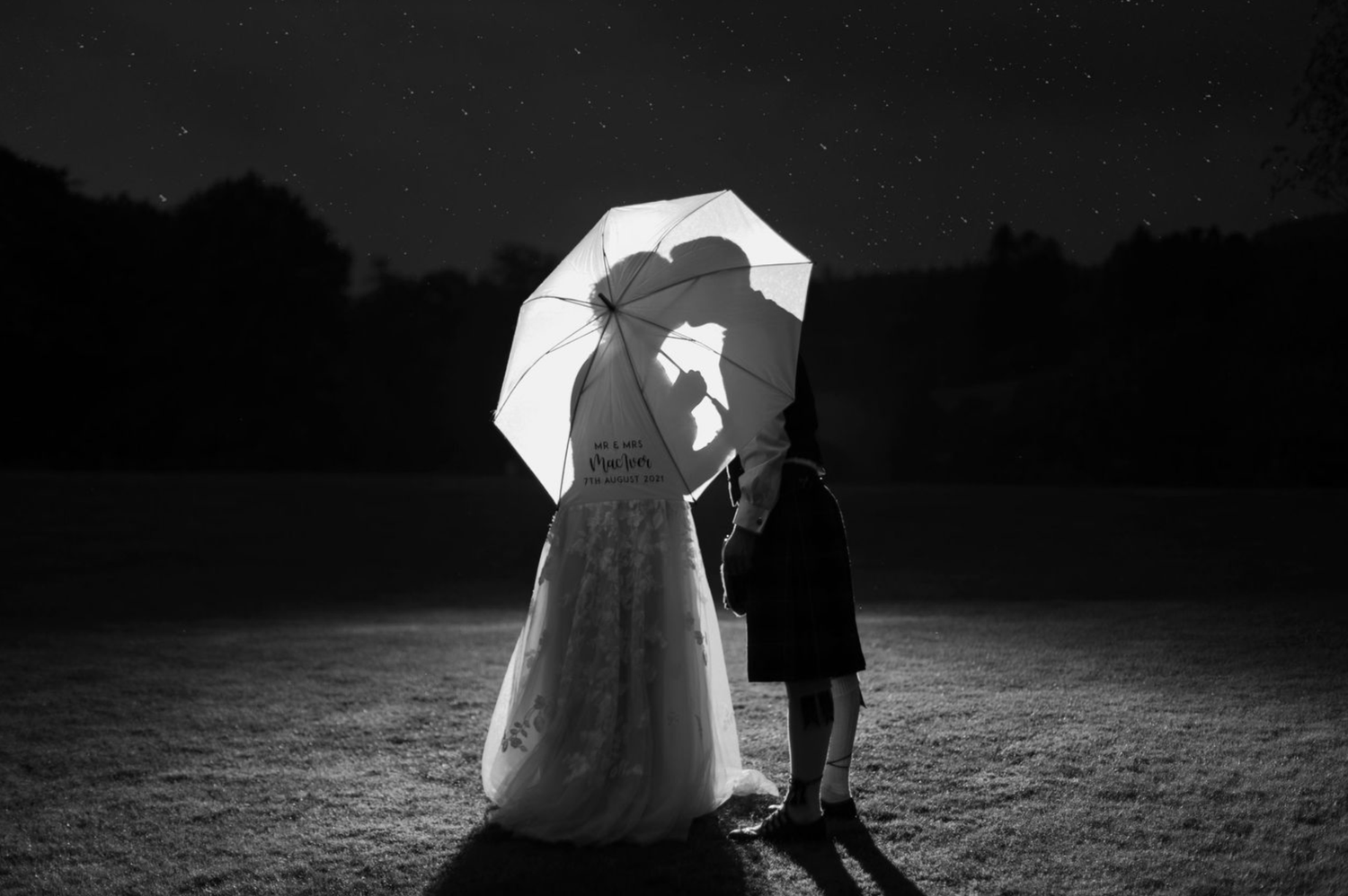 A black and white photograph shows two people dancing together in a romantic embrace on an outdoor dance floor.