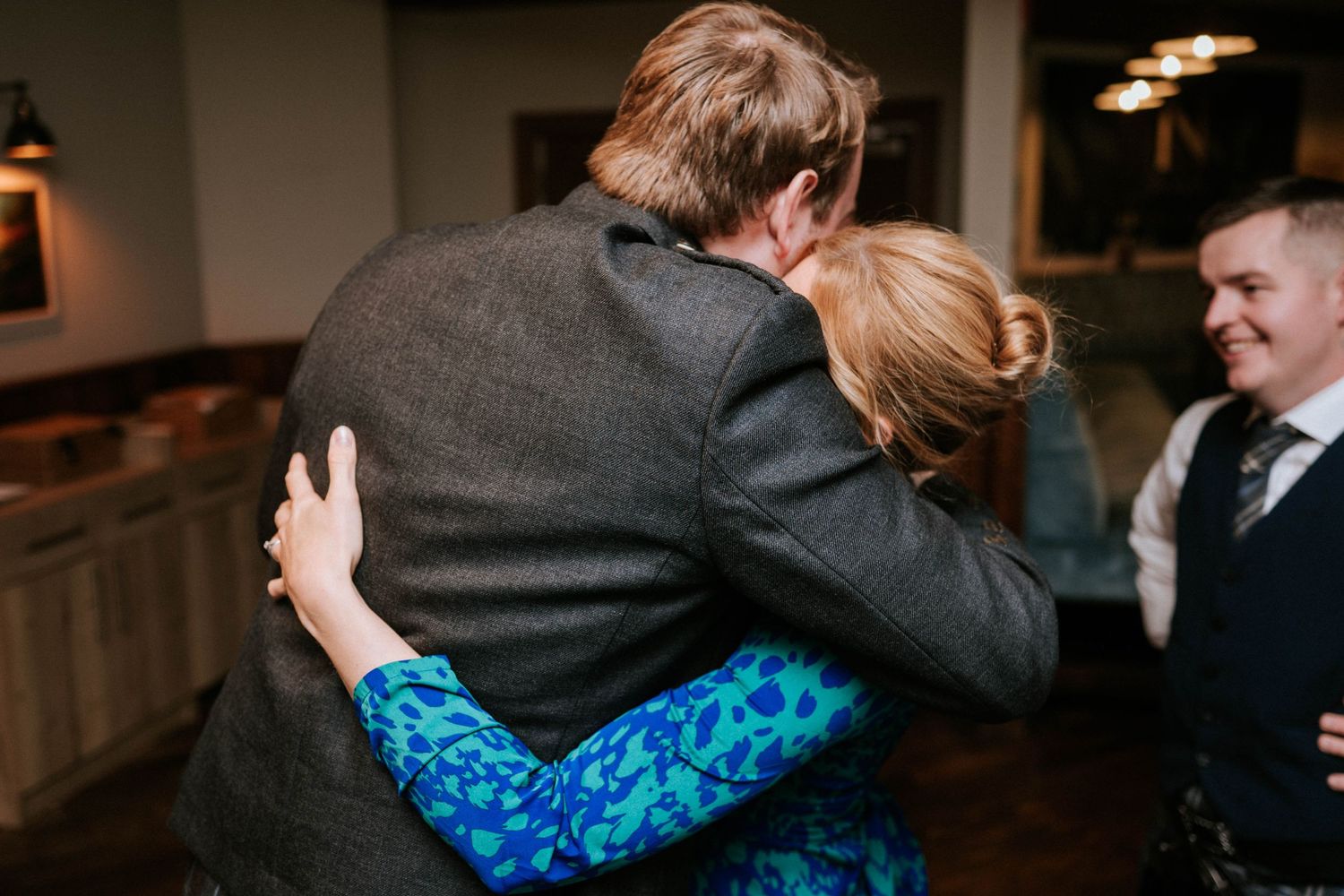 Wedding party celebrates with joyful expressions and dancing at an indoor reception venue.