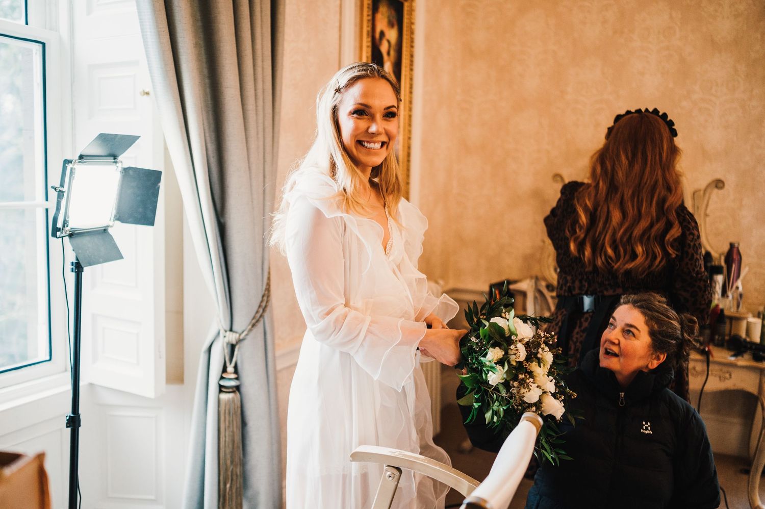 Wedding preparation scene in an elegantly decorated room with soft lighting and floral arrangements.