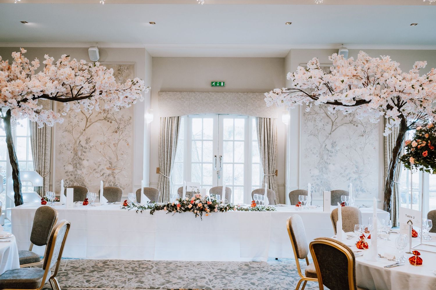 Wedding venue decorated with cherry blossom trees and elegant table settings.