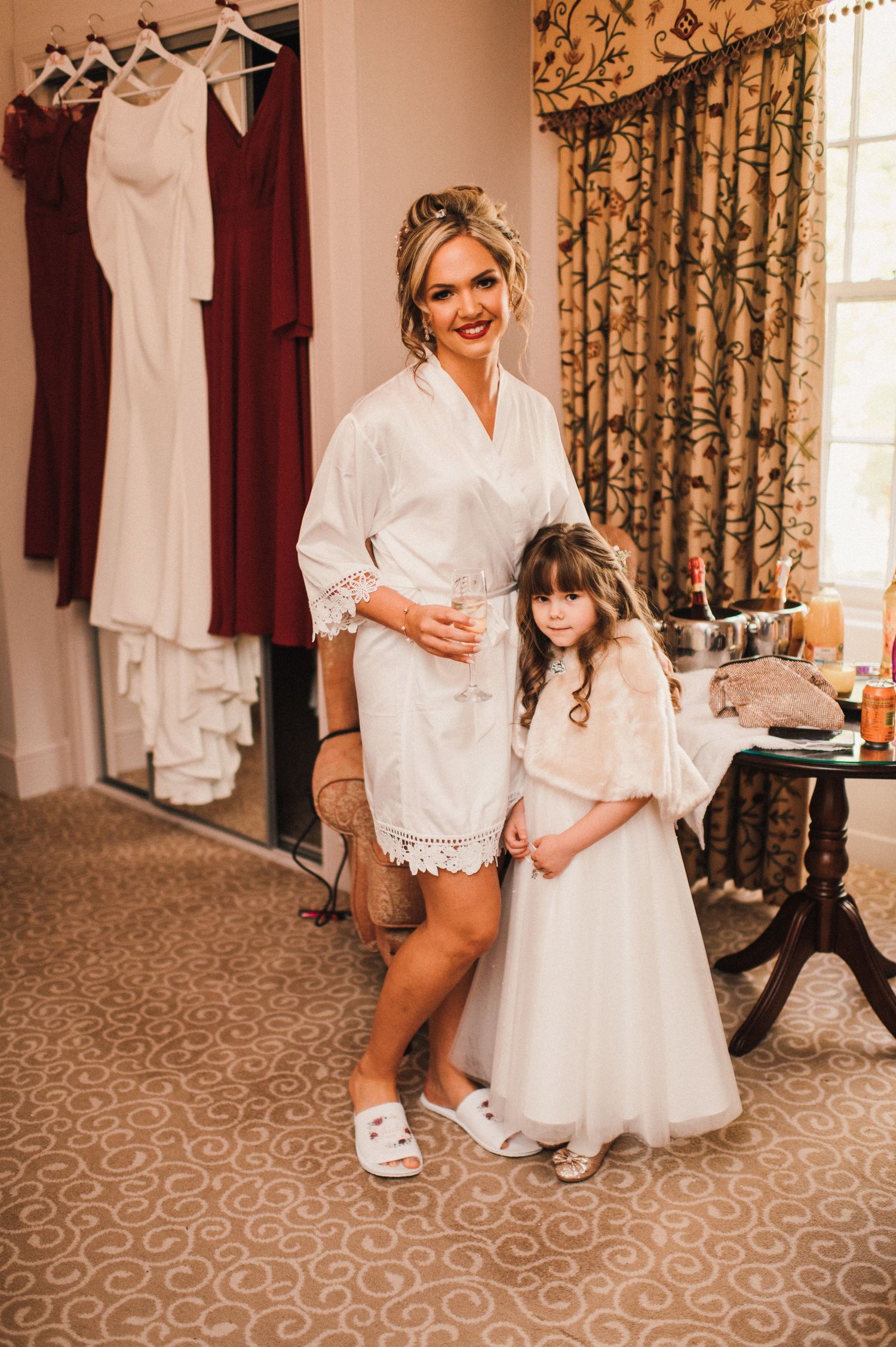 Getting ready scene with white and burgundy robes hanging in background of elegant room.