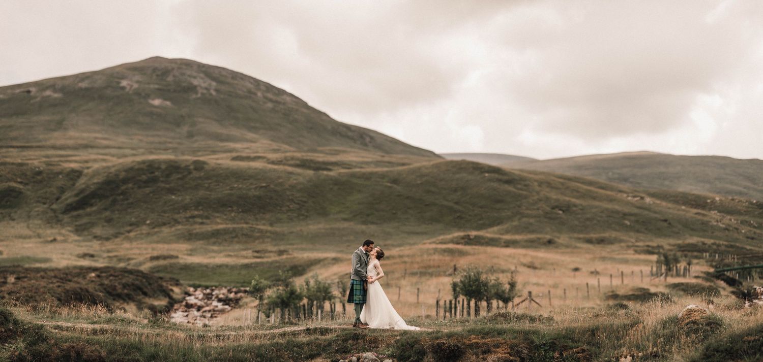 Wedding photograph with rolling Scottish hills and moody skies in the background.