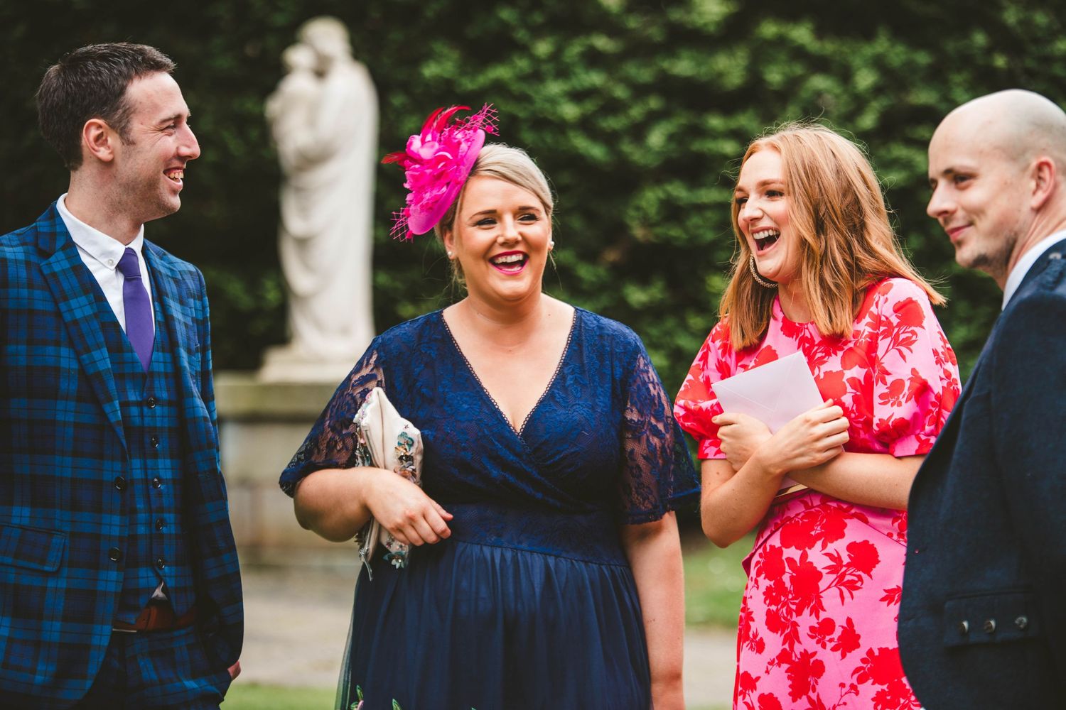 Wedding guests in colorful attire sharing a candid moment of laughter outdoors.