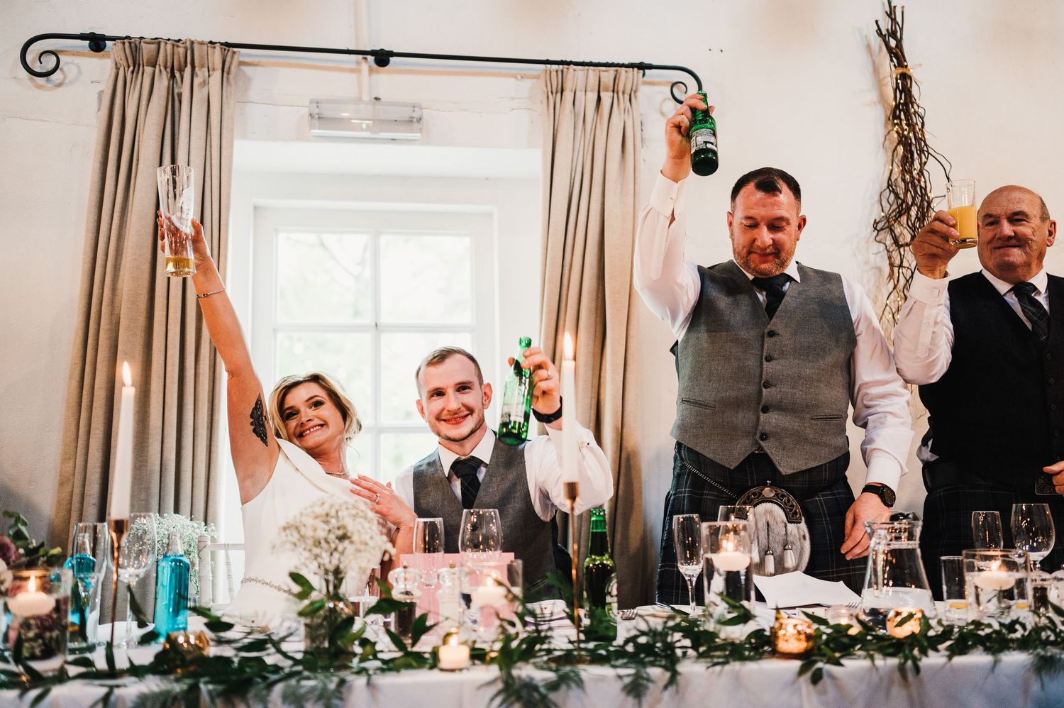 Elegant wedding reception table decorated with greenery garlands and candlelight.