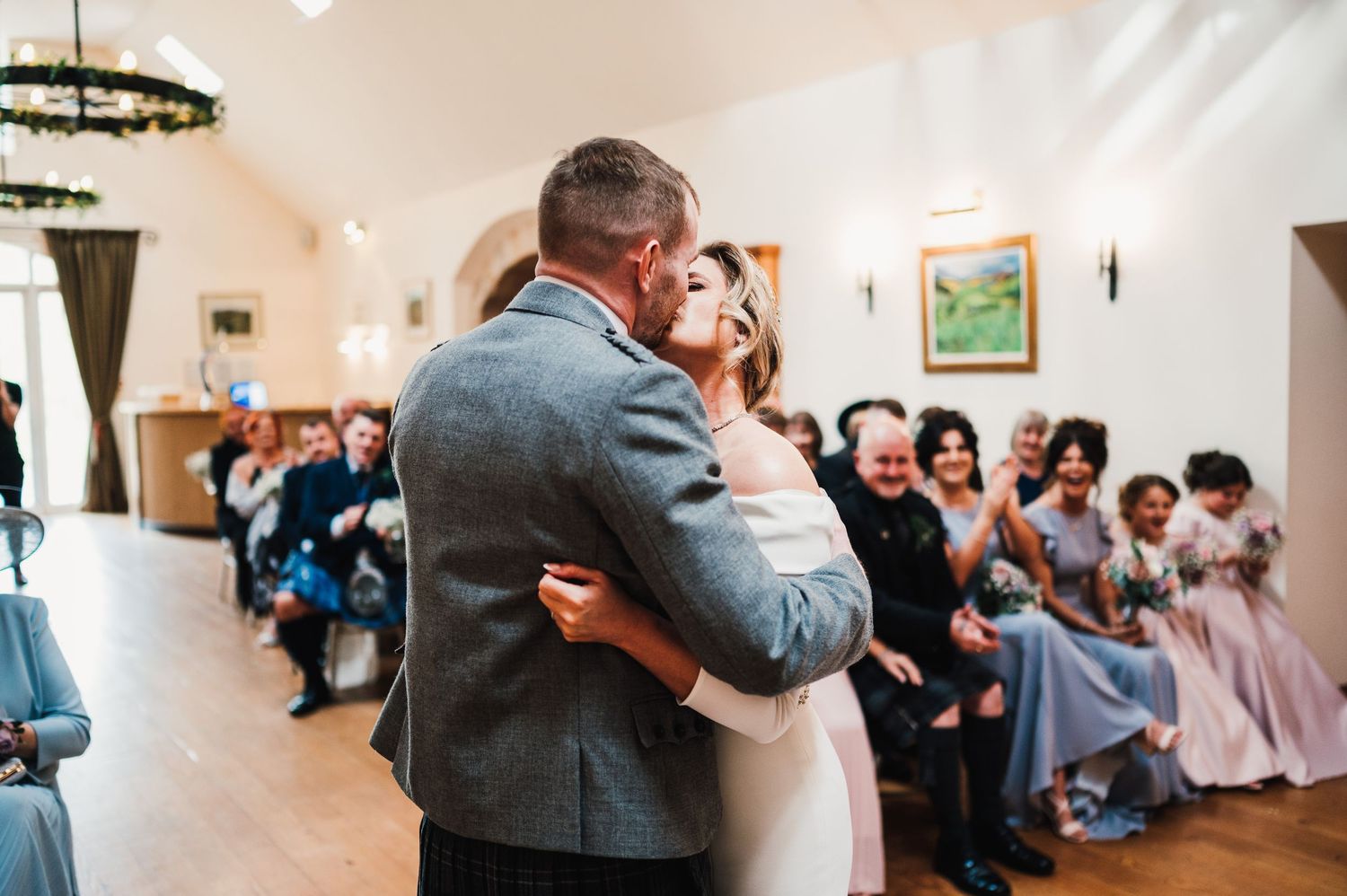 Wedding guests dancing and celebrating together on the dance floor at an indoor reception venue.