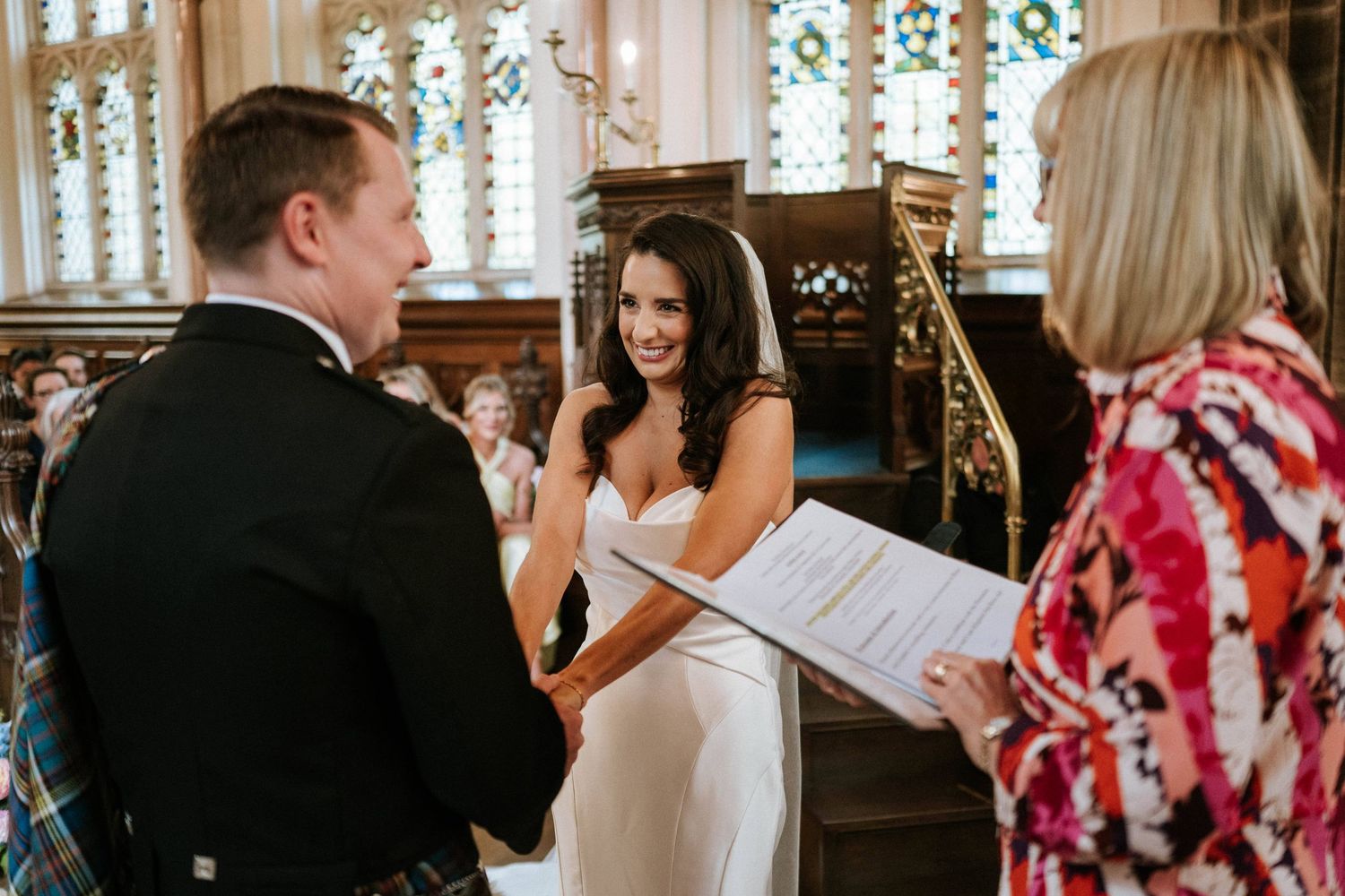 Wedding ceremony taking place in a traditional church with stained glass windows and ornate architecture.