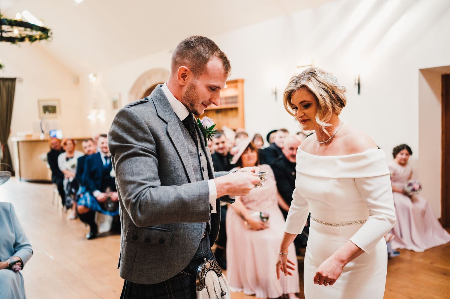 Wedding guests dancing and celebrating in a bright indoor venue.