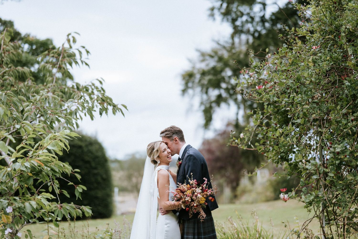 Wedding party gathered for outdoor photos in natural landscape setting.