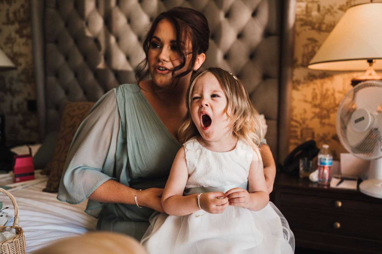 Playful candid moment captured on tufted furniture in vintage-styled room.