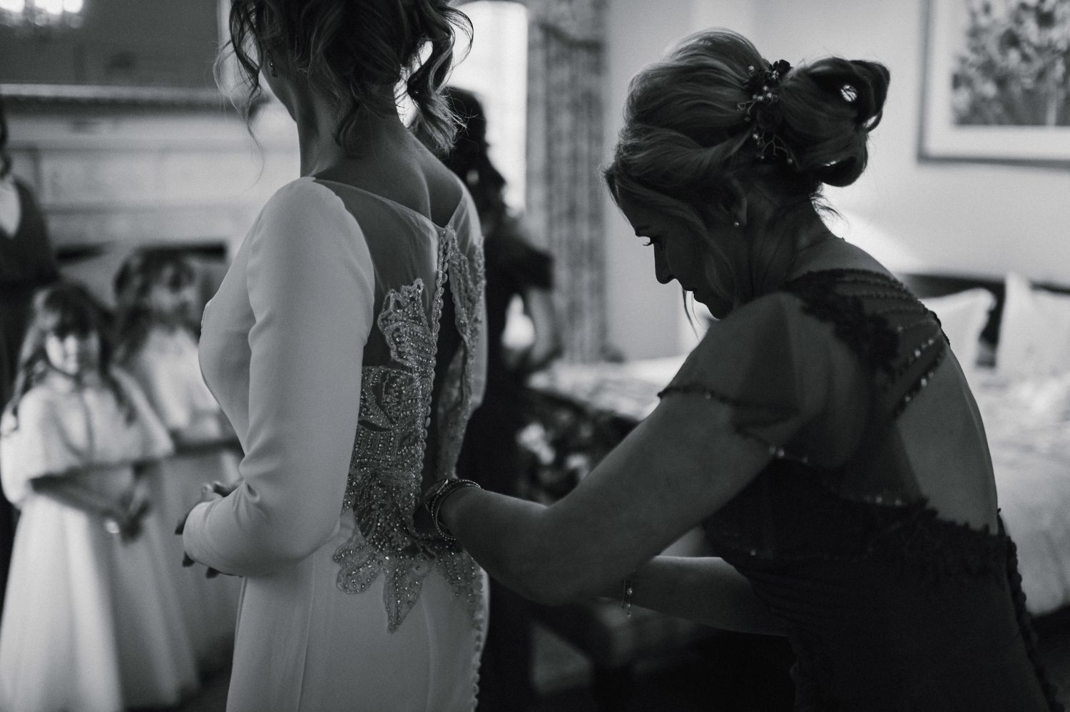 Black and white image capturing a tender dress adjustment moment.