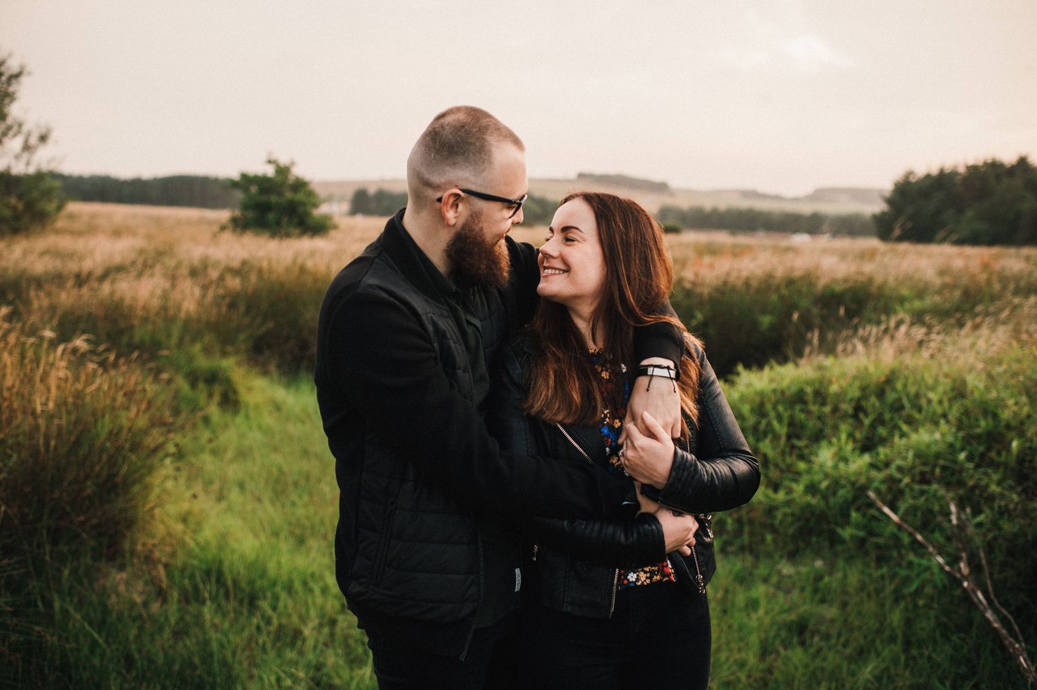 Tender embrace captured in natural grassland setting during golden hour.