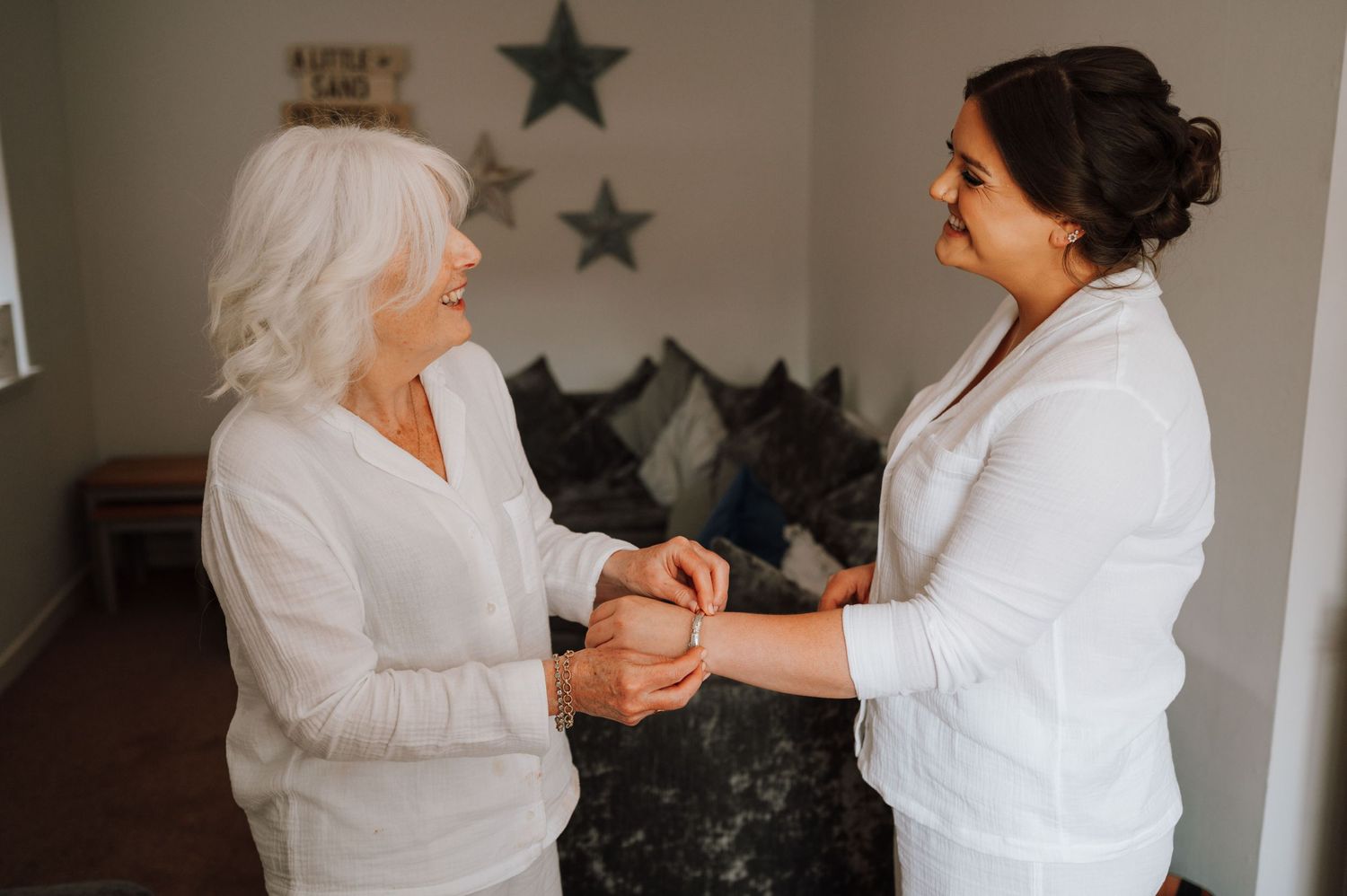 Two people in white outfits sharing a tender moment while holding hands indoors.
