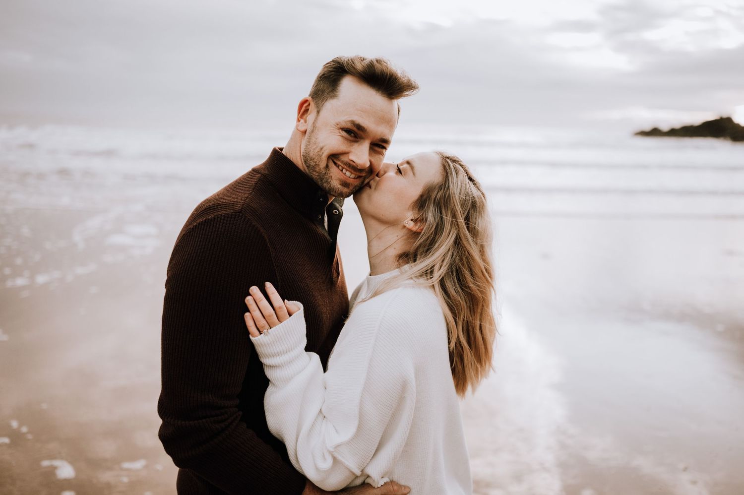 Joyful couple sharing an intimate moment while laughing on the beach.