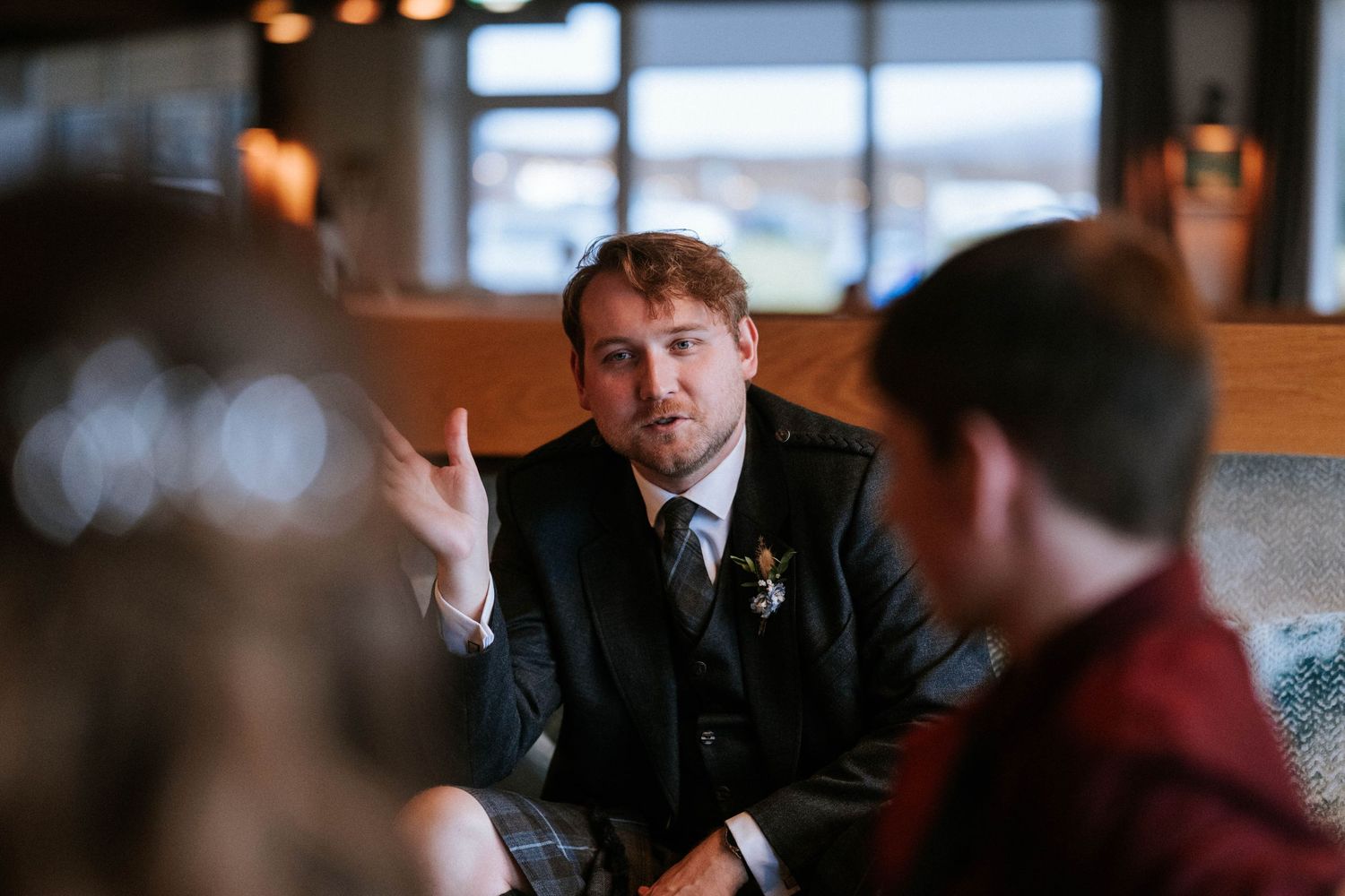 Candid moments during indoor wedding reception with natural window lighting.