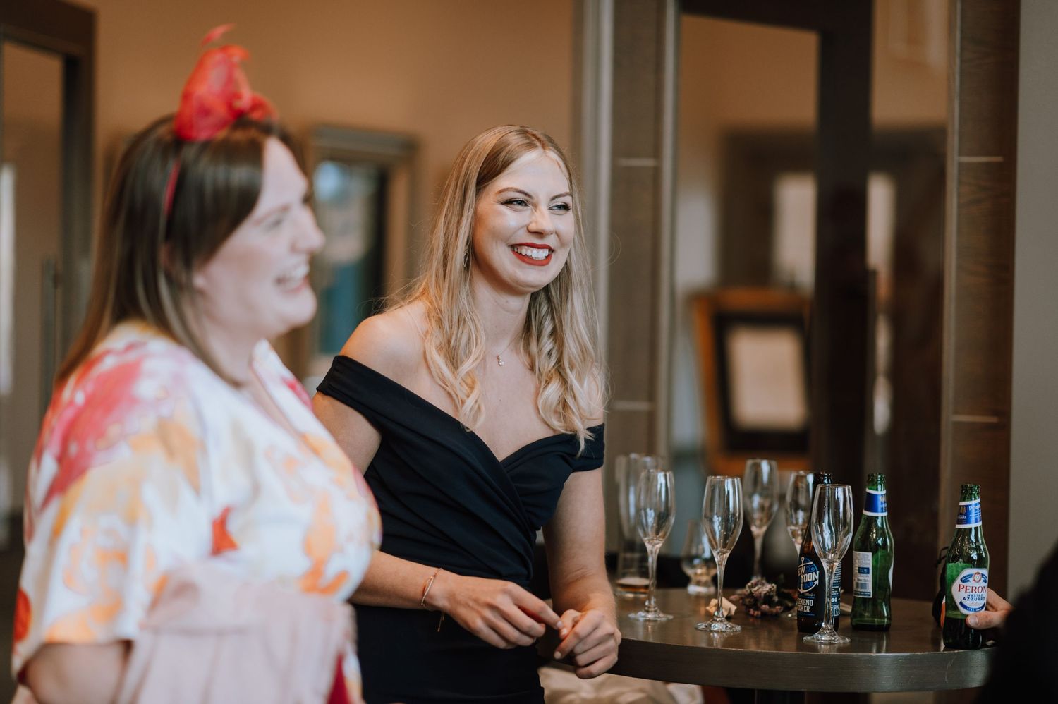 Wedding reception guests enjoying drinks and conversation at indoor bar.