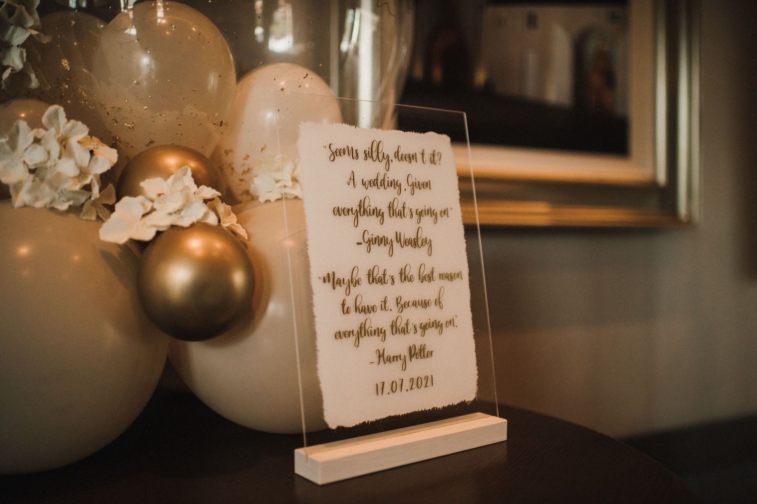 Wedding quote display with golden balloons and floral decorations in warm lighting.