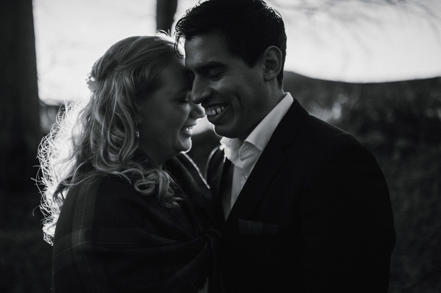 An intimate black and white portrait of a couple sharing a tender moment.