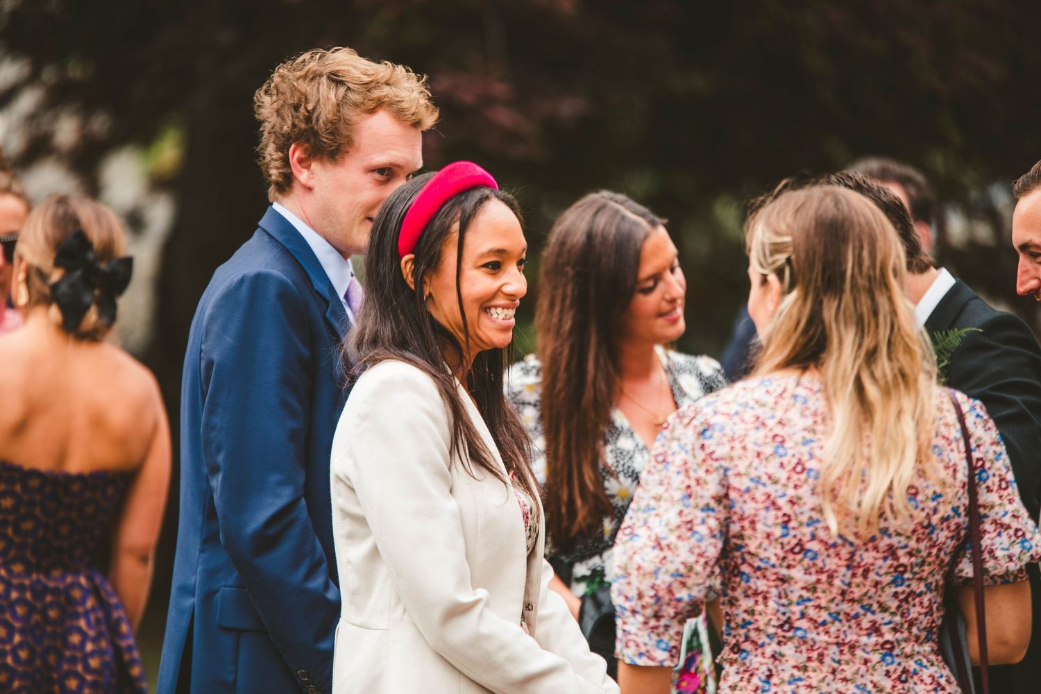 Wedding guests in formal attire socializing during an outdoor celebration.