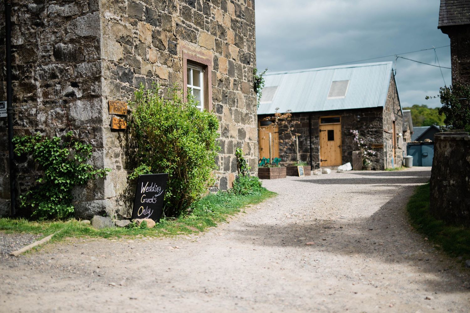 Stone buildings and pathway in a rustic village setting under cloudy skies.