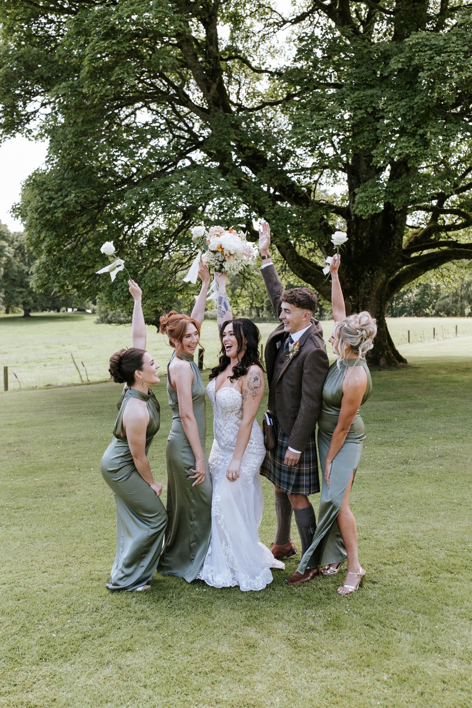 Fasque Castle Wedding Photography. Wedding party shares laughs during casual group photos on grassy lawn.