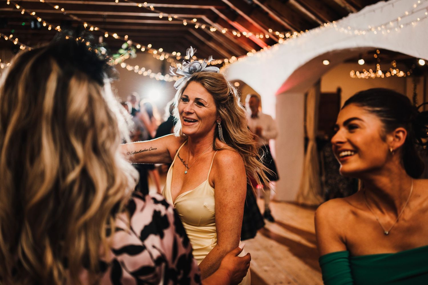 Joyful celebration on the dance floor during wedding reception under string lights.