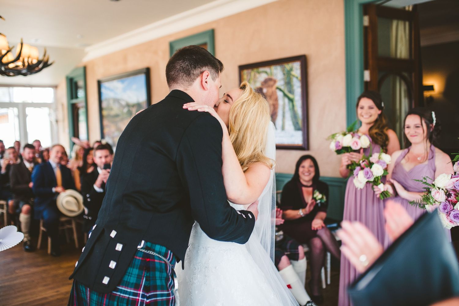 Wedding celebration with guests in traditional Scottish attire and formal wear.