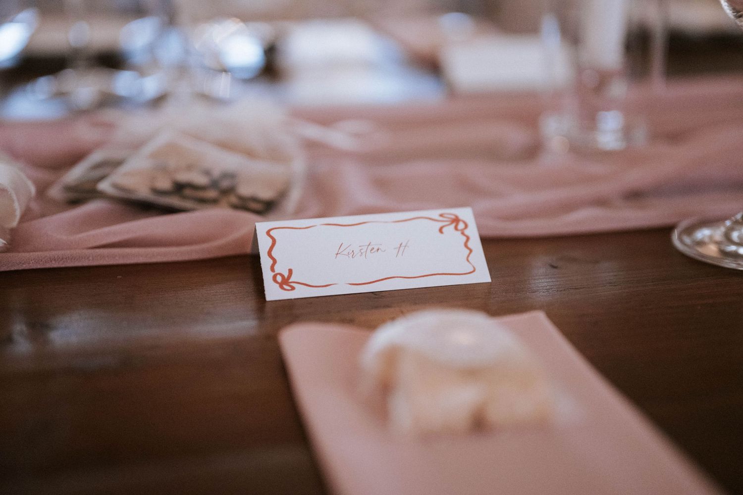 Wedding place cards and table settings arranged on a dark wooden surface.