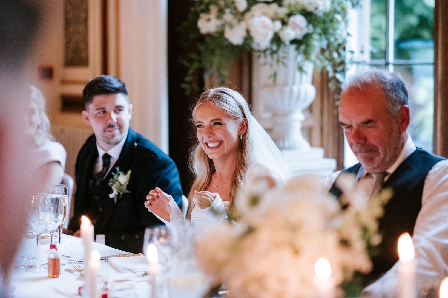 Wedding reception dinner with guests seated at decorated tables in natural light.