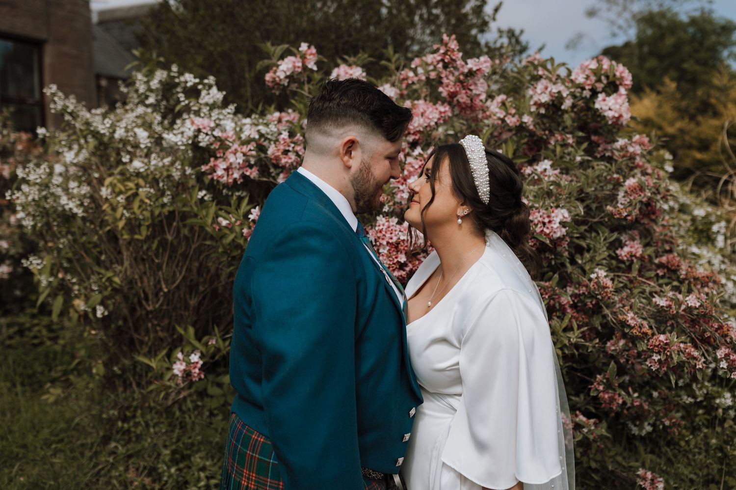 Romantic wedding portrait against blooming pink magnolia tree background.
