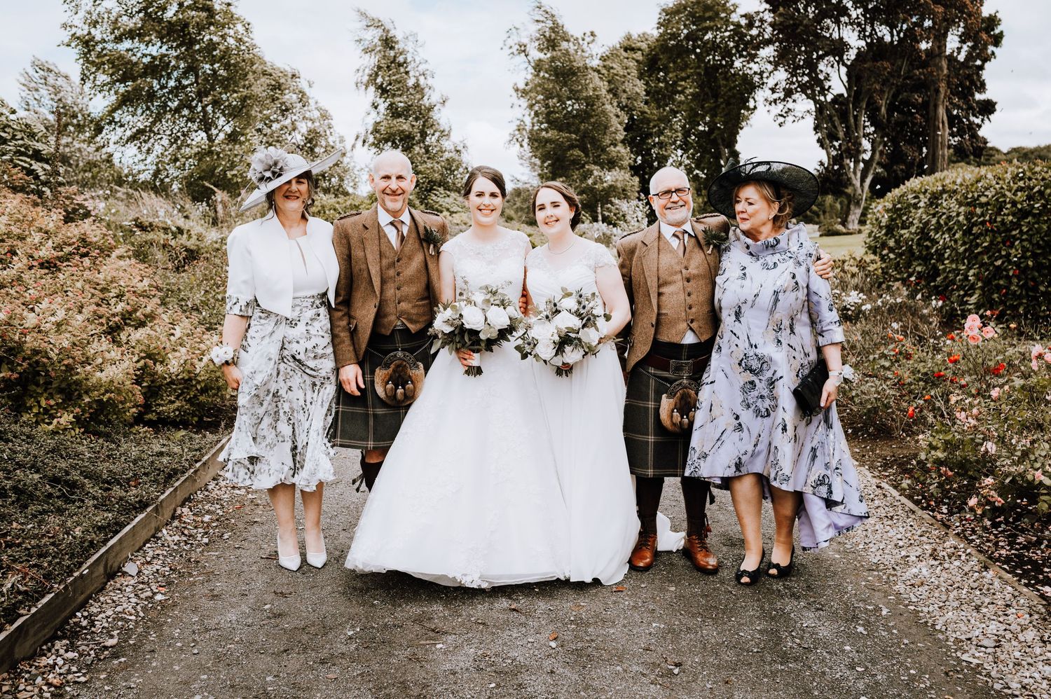Wedding party poses on a garden path with the wedding couple in traditional attire.