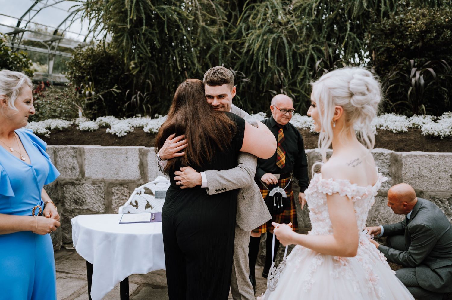 Emotional embraces shared during a greenhouse wedding celebration.