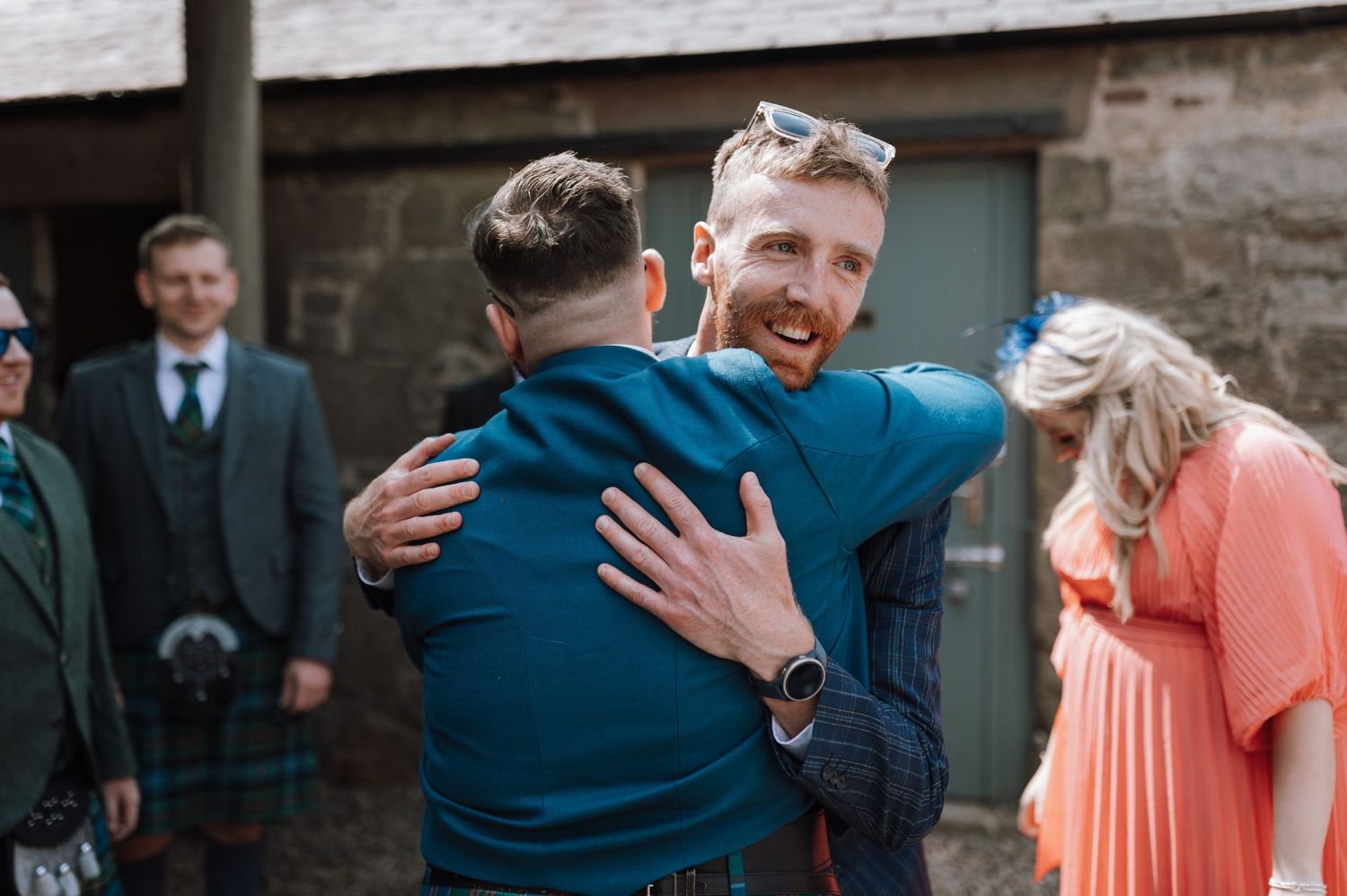 Emotional moment between guests hugging at outdoor wedding venue.