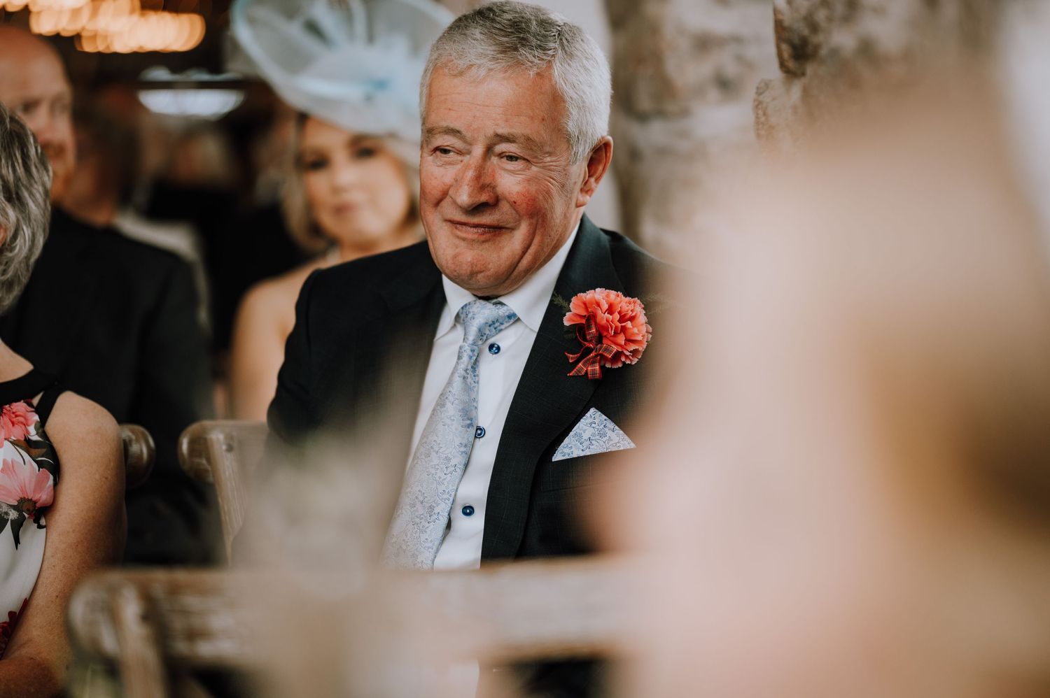Wedding guest enjoying the celebration with a bright coral boutonniere and blue tie.