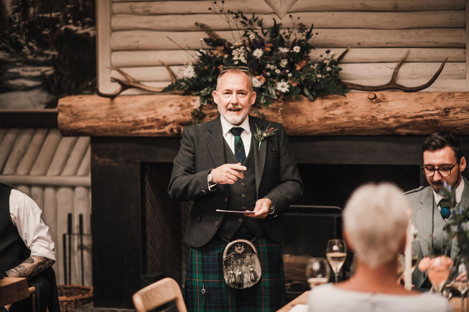 Traditional Scottish celebration in rustic venue with wooden beams and floral arrangements.