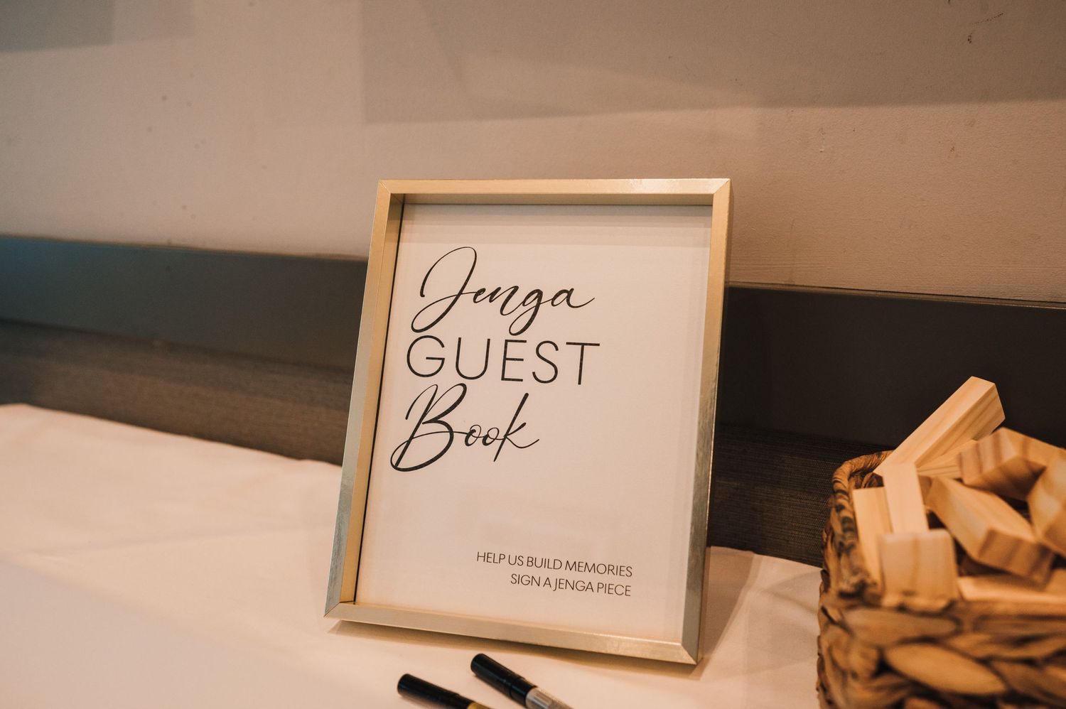 A framed guestbook sign sits on a table with calligraphy lettering.