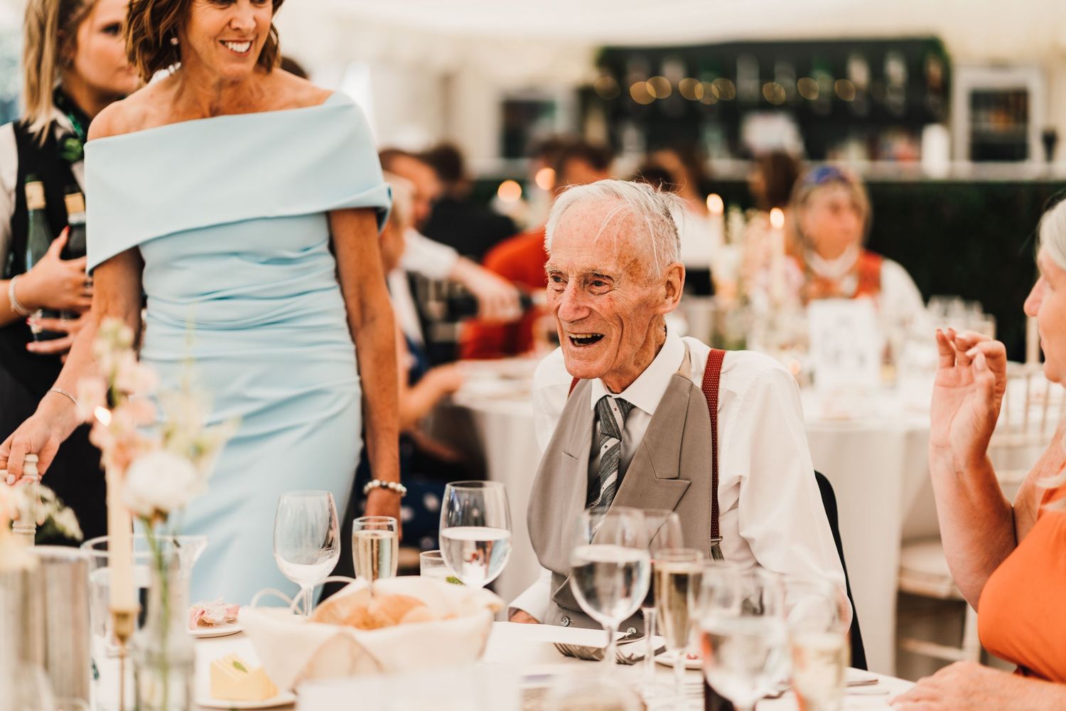 Festive wedding reception scene with guests enjoying dinner at elegantly set tables.