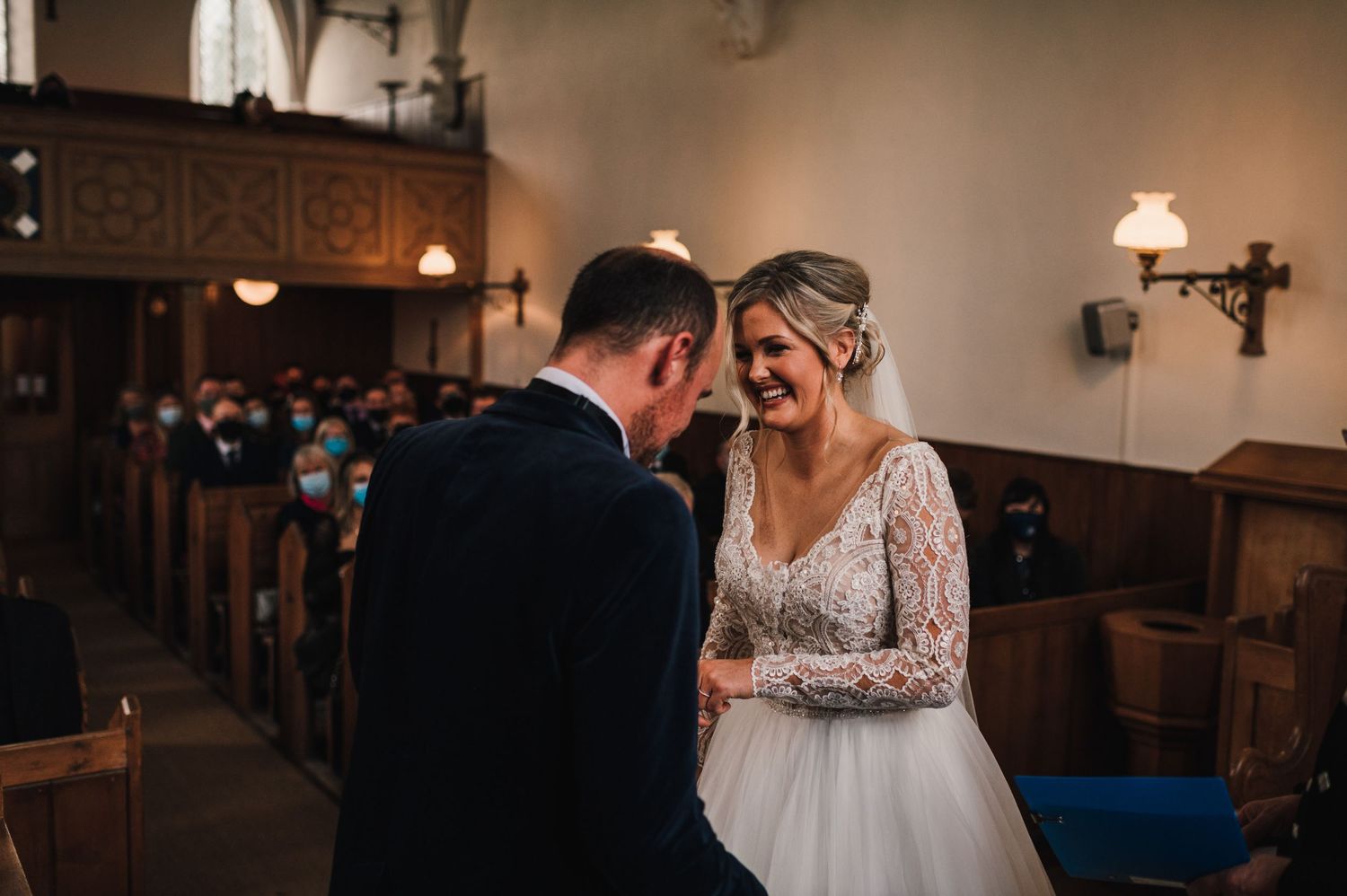 An intimate wedding moment captured in a traditional church setting with wooden pews.